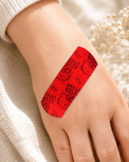 Gros plan sur la main d’une personne portant le pansement pailleté rouge Hello Kitty, posé délicatement sur la peau.