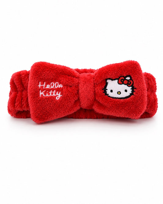 Vue de face d’un bandeau pour cheveux de soin rouge en tissu éponge doux, orné d’un grand nœud central avec broderie Hello Kitty.