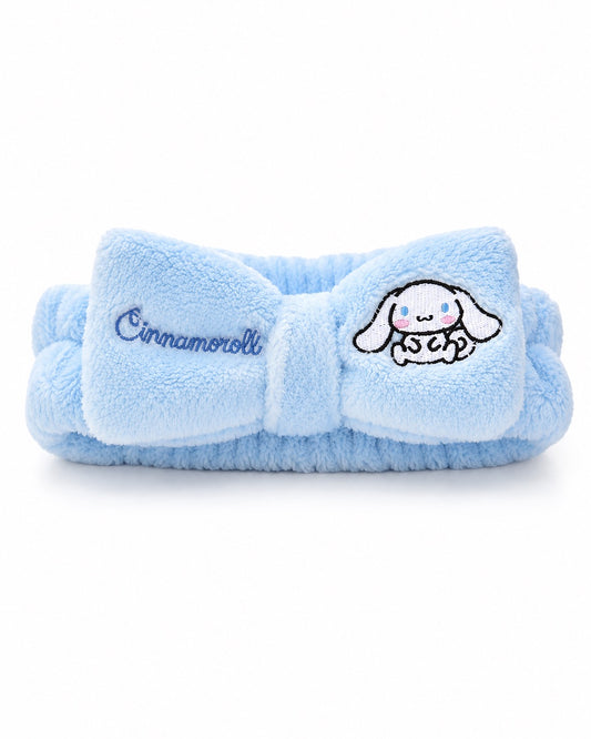 Bandeau de tête élastique en peluche bleu ciel avec un grand nœud central brodé du nom et du personnage Cinnamoroll de Sanrio.