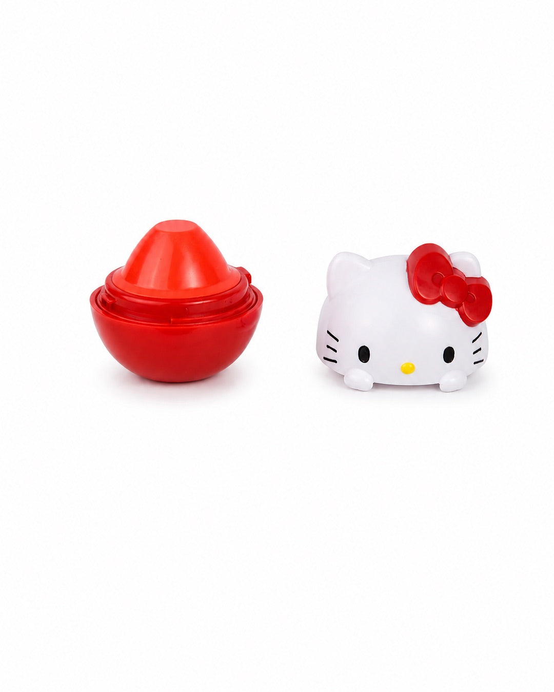 Baume à lèvres Hello Kitty dévissé montrant le dôme de soin rouge à la cerise à côté de son capuchon en forme de tête de mascotte.