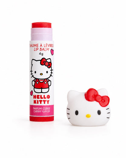 Tube de baume à lèvres inclus dans le coffret Hello Kitty, ouvert révélant le stick de soin hydratant rouge, avec son bouchon en forme de tête posé juste à côté.