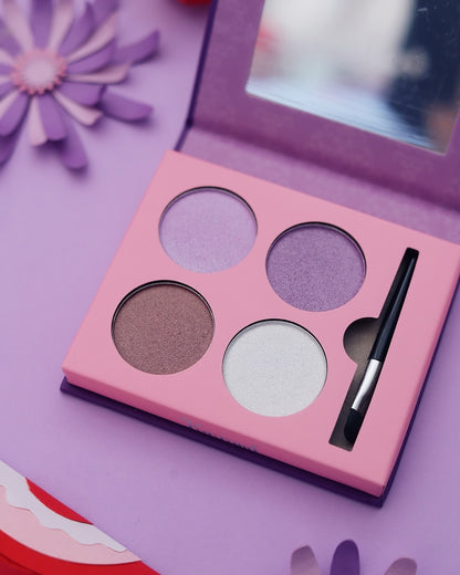 Palette de fards à paupières Kuromi ouverte montrant un miroir intégré, un pinceau applicateur et 4 teintes de fards (violet, mauve, brun et blanc). Gros plan, dans une ambiance