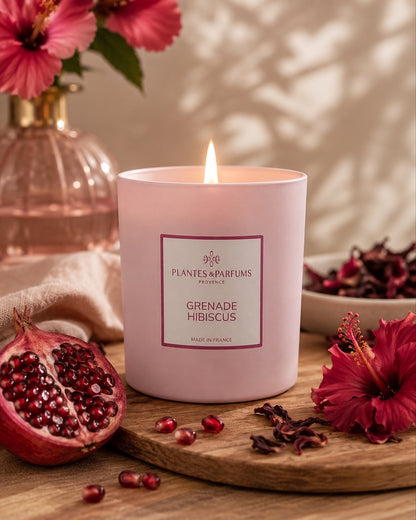 Bougie parfumée 180 g, fragrance Grenade & Hibiscus de Plantes & Parfums à la cire de soja dans un contenant en verre rose mat, ambiance florale.