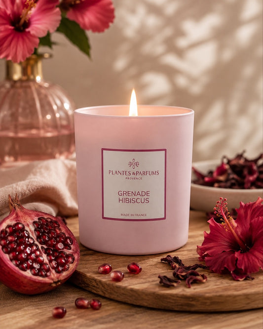 Bougie parfumée 180 g, fragrance Grenade & Hibiscus de Plantes & Parfums à la cire de soja dans un contenant en verre rose mat, ambiance florale.