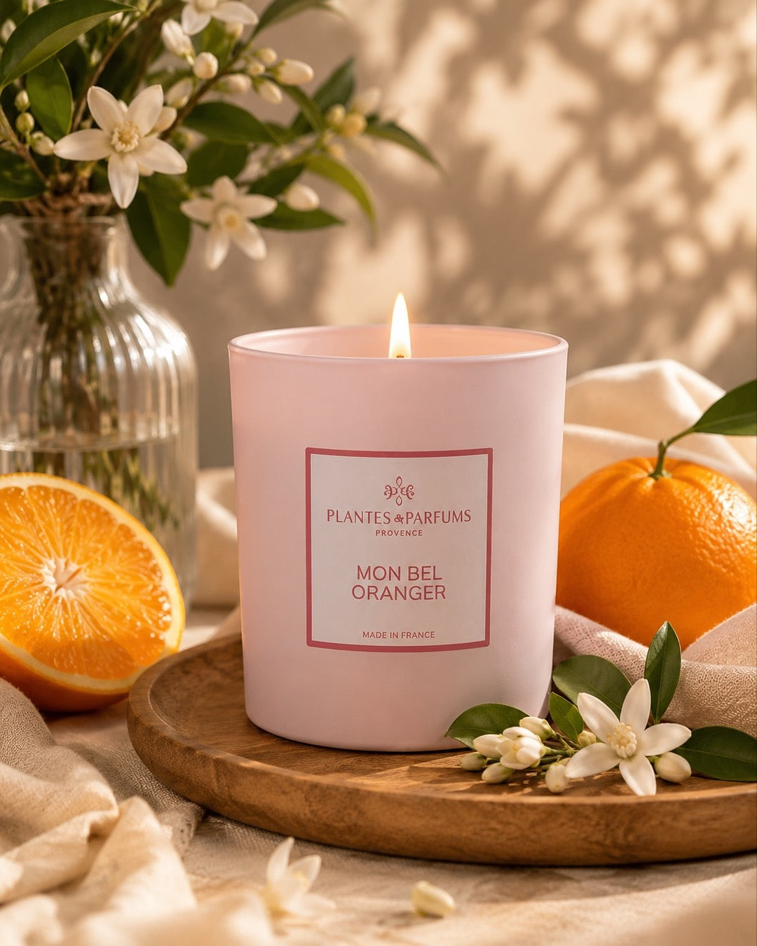 Bougie parfumée 180 g, fragrance Mon bel oranger de Plantes & Parfums à la cire de soja dans un contenant en verre rose mat, ambiance florale.