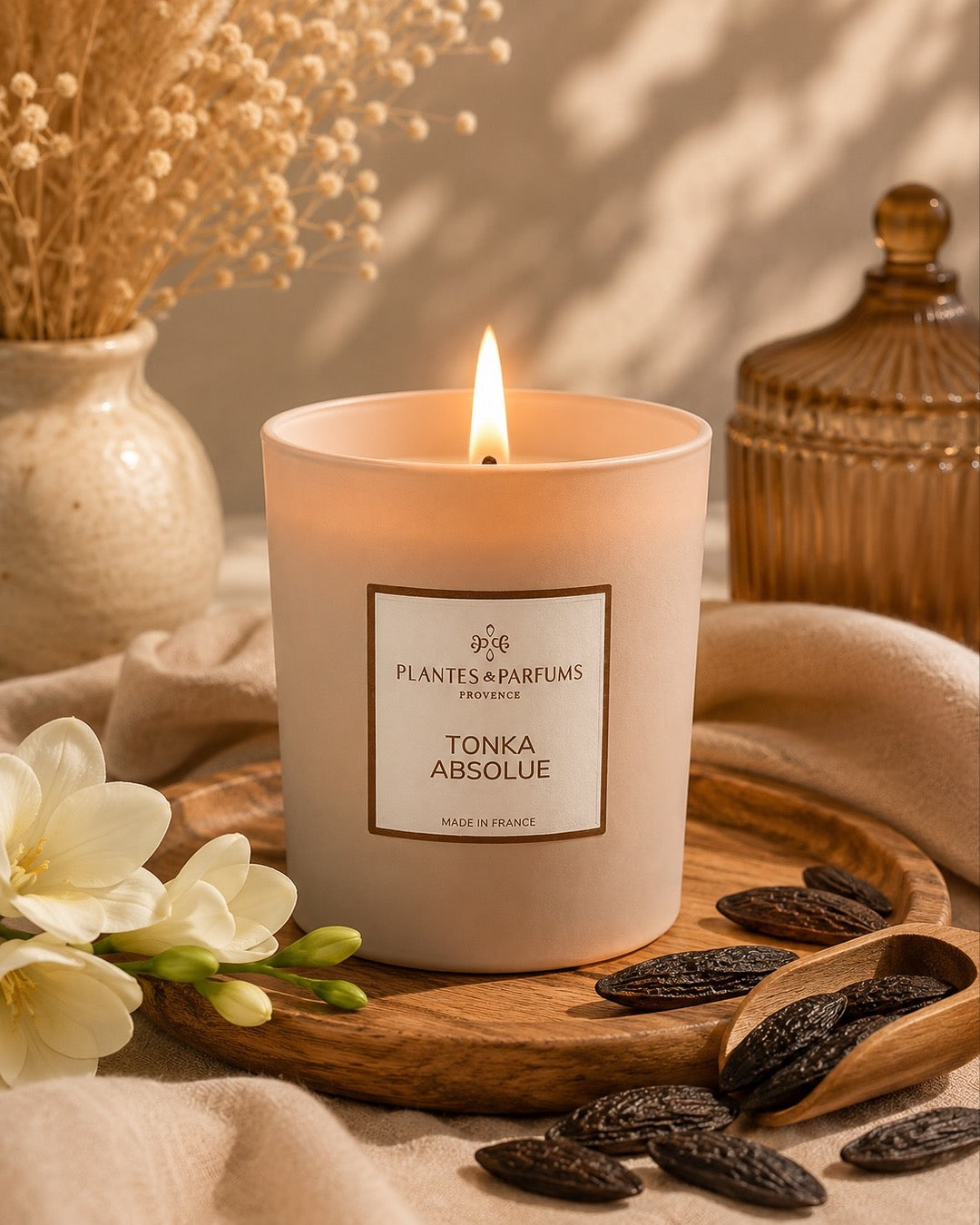 Bougie parfumée 180 g, fragrance Tonka absolue de Plantes & Parfums à la cire de soja dans un contenant en verre beige mat, ambiance boisée.
