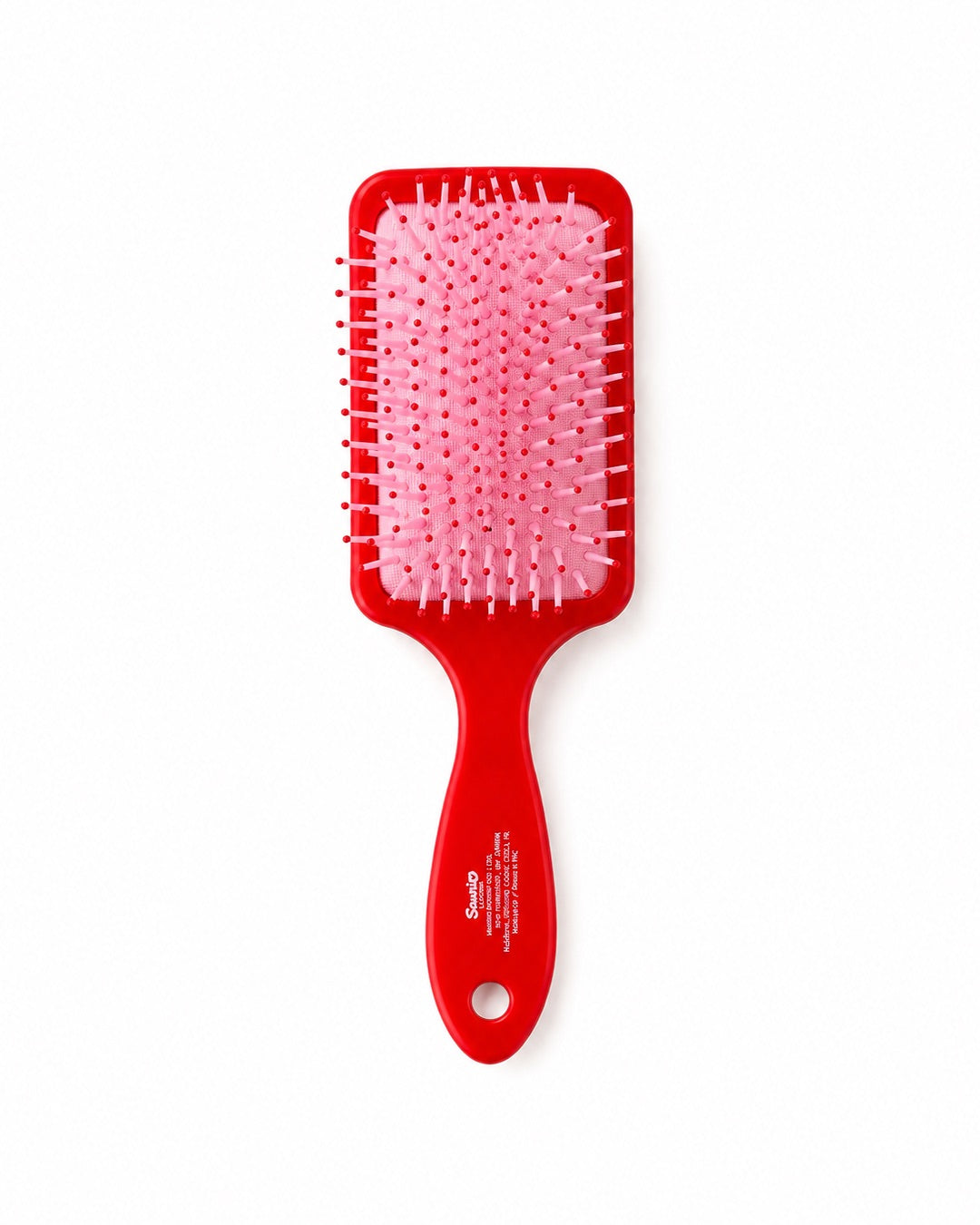 Vue de l’arrière de la brosse à cheveux montrant le coussin pneumatique rose souple et les picots de démêlage à bouts ronds.