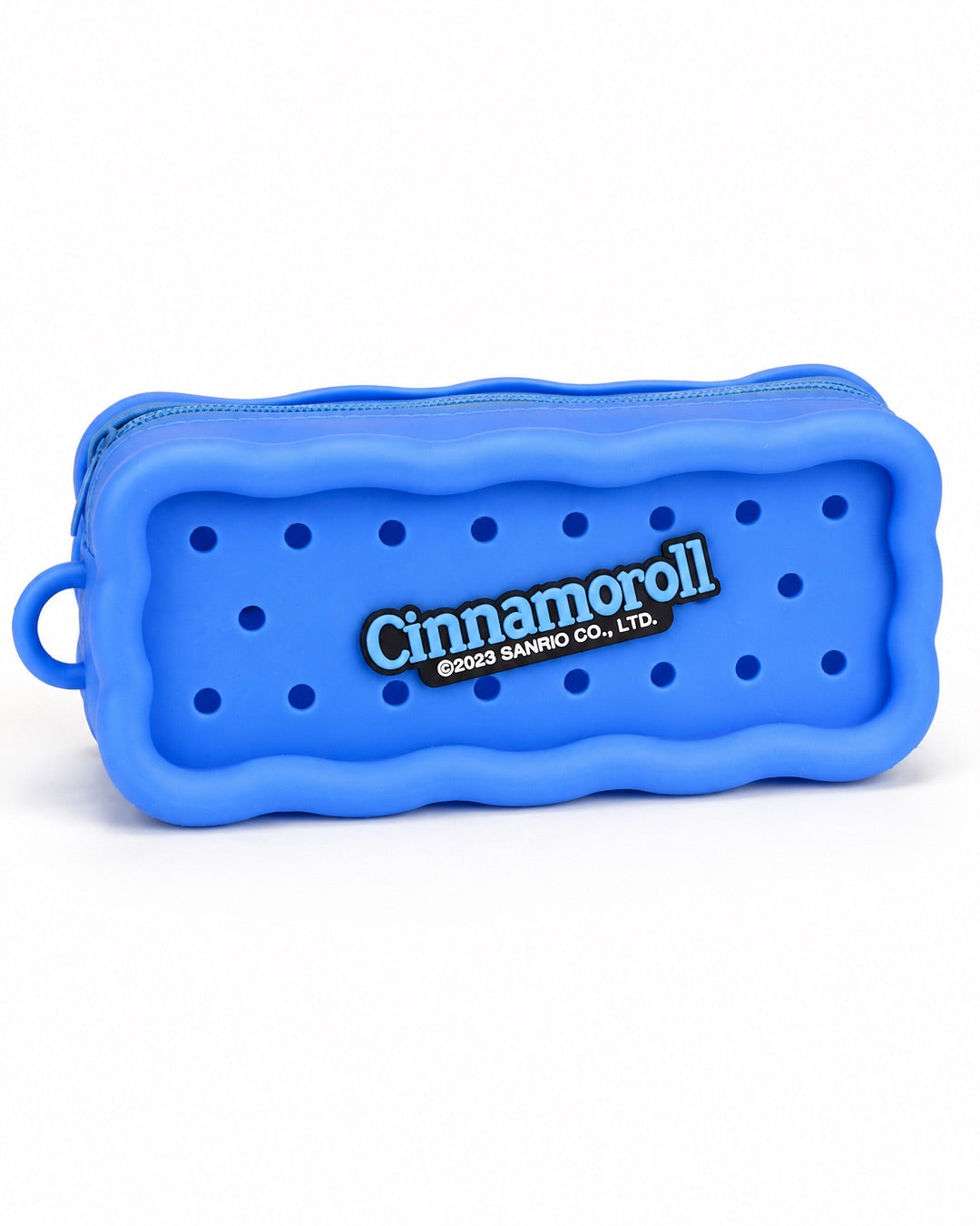Trousse rectangulaire en silicone bleu avec des perforations contenant trois pins amovibles du personnage Cinnamoroll et de desserts.