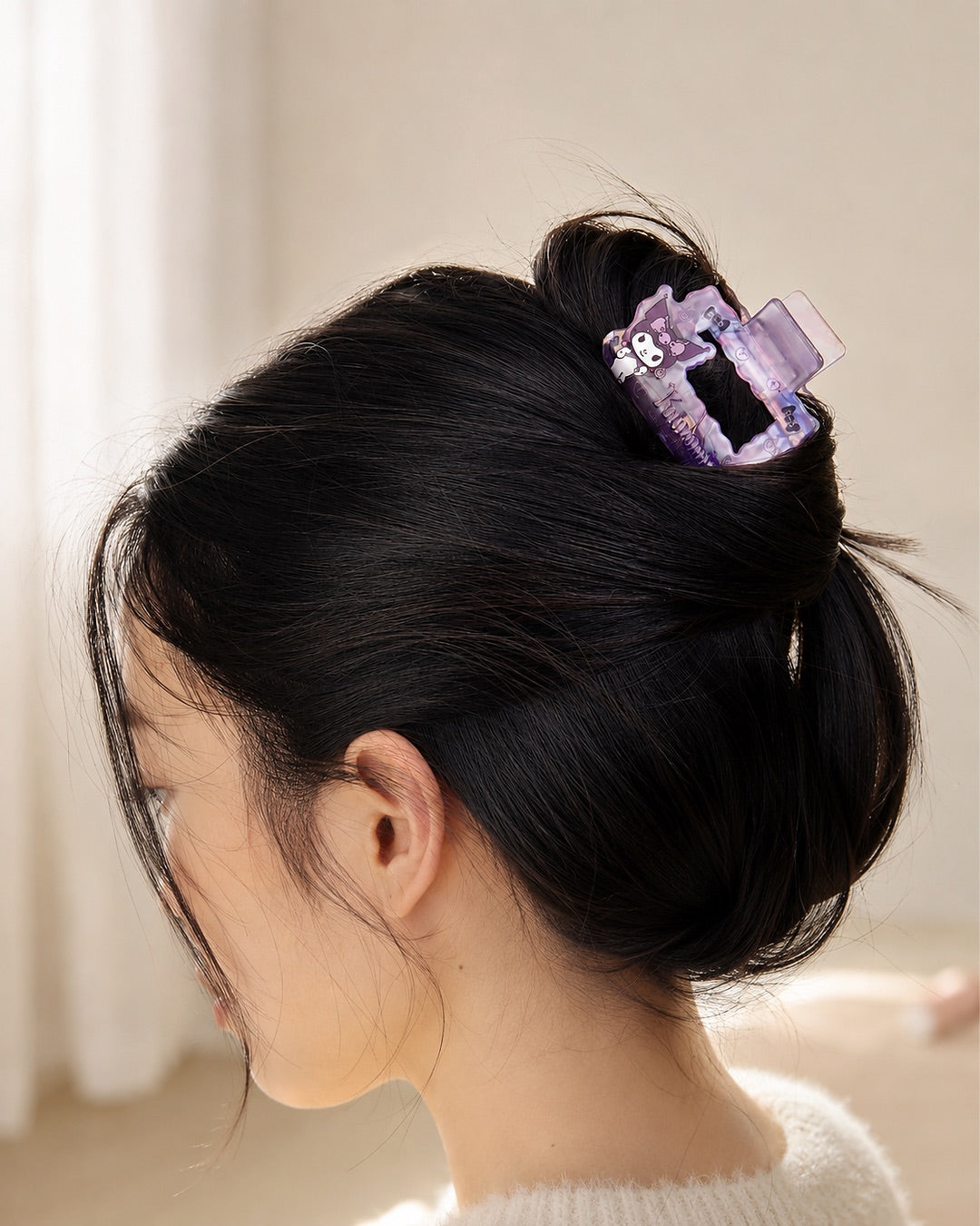 Profil d'une femme portant la petite pince à cheveux carrée ondulée mauve Kuromi Sanrio avec une coiffure de style chignon.