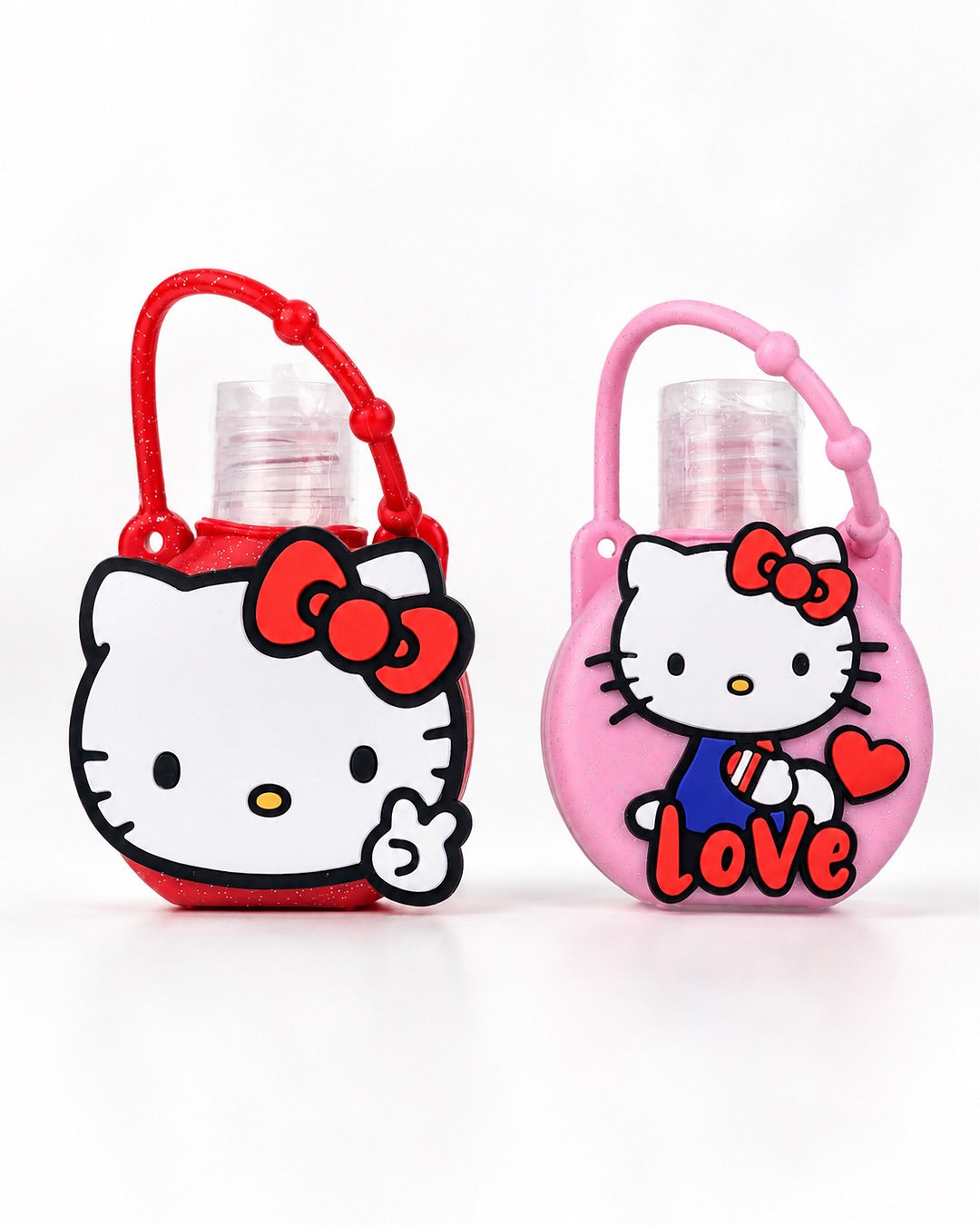 Vue de face de deux flacons à presser de gel nettoyant pour les mains Hello Kitty : l’un à gauche dans un étui en silicone rouge pailleté à l’effigie de la mascotte, et l’autre à droite dans un étui en silicone rose marqué du mot Love.