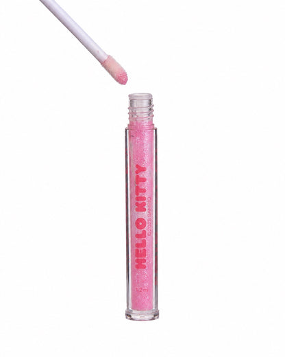 Vue de face du long tube transparent dévissé montrant l’applicateur en mousse imbibé de gloss liquide rose pailleté.