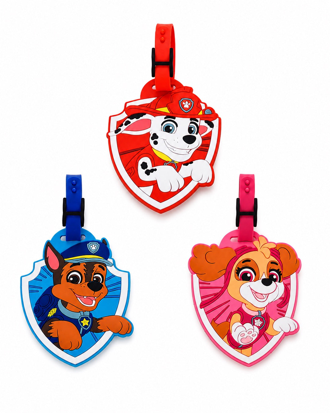 Trois étiquettes à bagage officielles La Pat' Patrouille en silicone souple en forme de blasons en relief représentant Marcus (rouge), Chase (bleu) et Stella (rose). Chaque modèle comprend une sangle de fixation ajustable de couleur assortie munie d'un passant de sécurité noir.