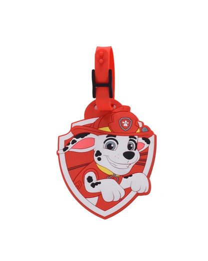 Étiquette à bagage officielle La Pat' Patrouille en silicone souple rouge en forme de blason en relief, représentant le visage de Marcus avec son chapeau de pompier. Une sangle ajustable rouge avec un passant noir est attachée au sommet.