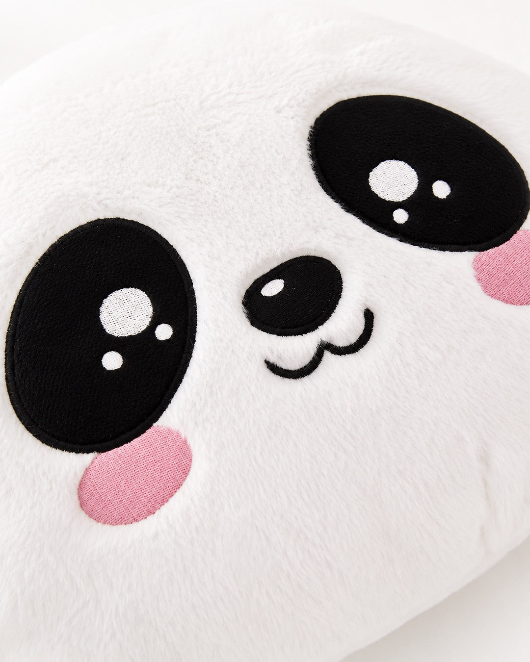 Gros plan sur le visage brodé d’un panda en peluche blanche douce avec des grands yeux noirs et des joues roses.