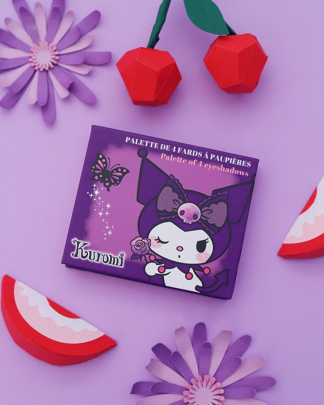 Vue de face de la boîte fermée violette d'une palette de 4 fards à paupières Kuromi Sanrio avec un motif de papillon. Dans une amniance