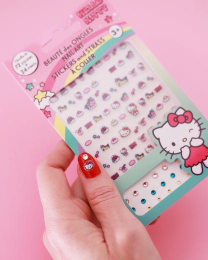 Main d’une femme tenant le kit de nail art Hello Kitty, mettant en valeur un ongle verni en rouge décoré d’un autocollant et d’un strass.