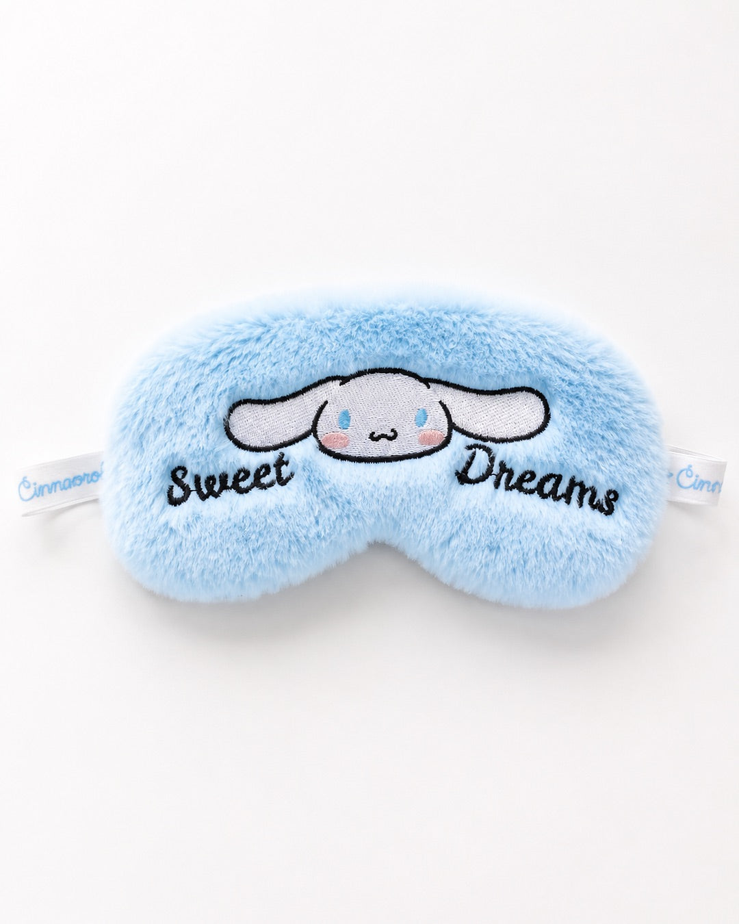Masque de nuit en peluche bleu doux avec broderie de Cinnamoroll et texte Sweet Dreams sur son emballage d'origine.