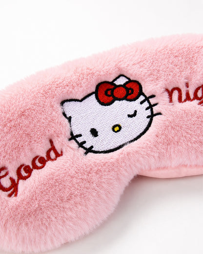 Gros plan détaillé sur la broderie centrale du masque de nuit, montrant le visage d’Hello Kitty faisant un clin d’œil et le texte texturé.