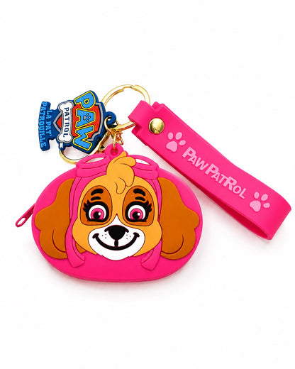 Mini porte-monnaie rose officiel La Pat' Patrouille en silicone souple représentant le visage en relief du personnage de Stella. Il comprend une fermeture éclair, une lanière de poignet rose avec logo, un anneau doré et une breloque officielle bilingue.