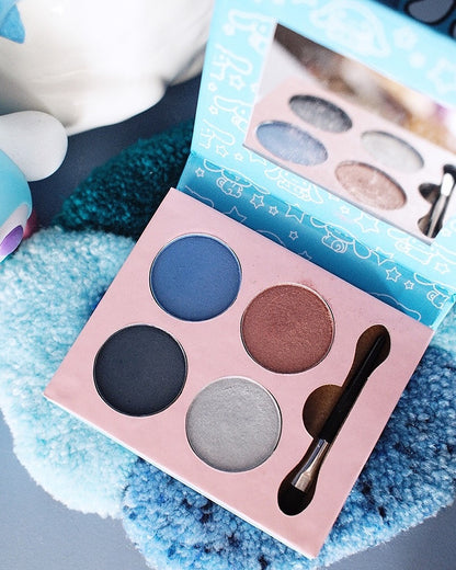 Une palette de fards à paupières Sanrio Cinnamoroll à 4 couleurs ouverte, comprenant des teintes mates et irisées de bleu, gris foncé, brun et argent, avec un applicateur double embout et un miroir intégré.