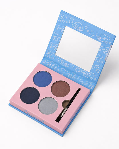Une palette de fards à paupières Sanrio Cinnamoroll à 4 couleurs ouverte, comprenant des teintes mates et irisées de bleu, gris foncé, brun et argent, avec un applicateur double embout et un miroir intégré.