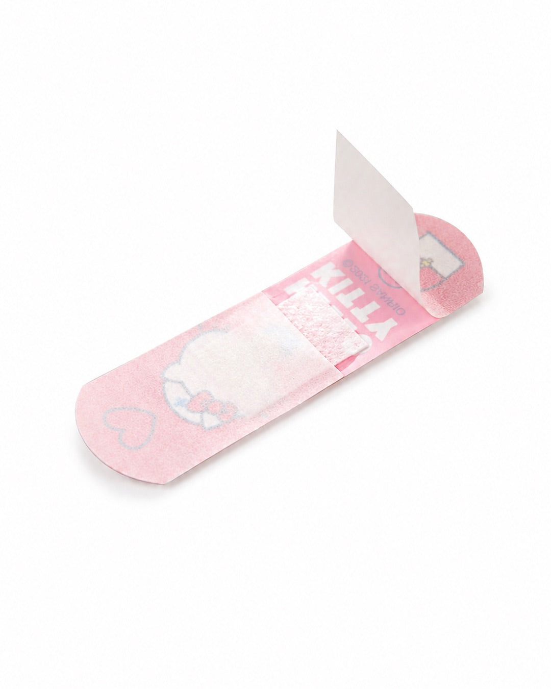 Vue de la face interne d’un pansement Hello Kitty rose dont la bande de protection blanche est soulevée pour montrer la compresse centrale.