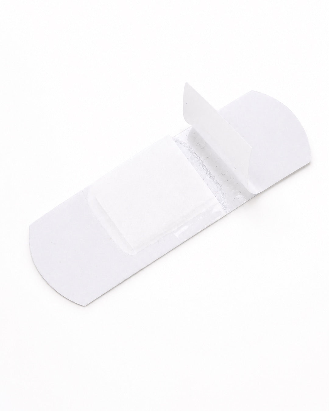 Vue de la face interne blanche d’un pansement pailleté Hello Kitty avec ses bandes de protection transparentes légèrement soulevées.