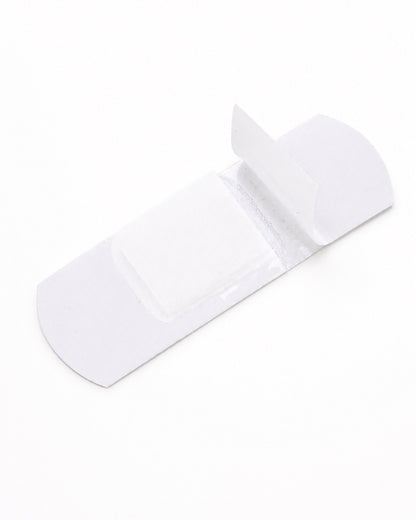 Vue de la face interne blanche d’un pansement pailleté Hello Kitty avec ses bandes de protection transparentes légèrement soulevées.