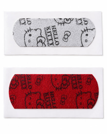 Vue à plat de deux pansements individuels Hello Kitty scintillants, l’un recouvert de paillettes argentées et l’autre de paillettes rouges.