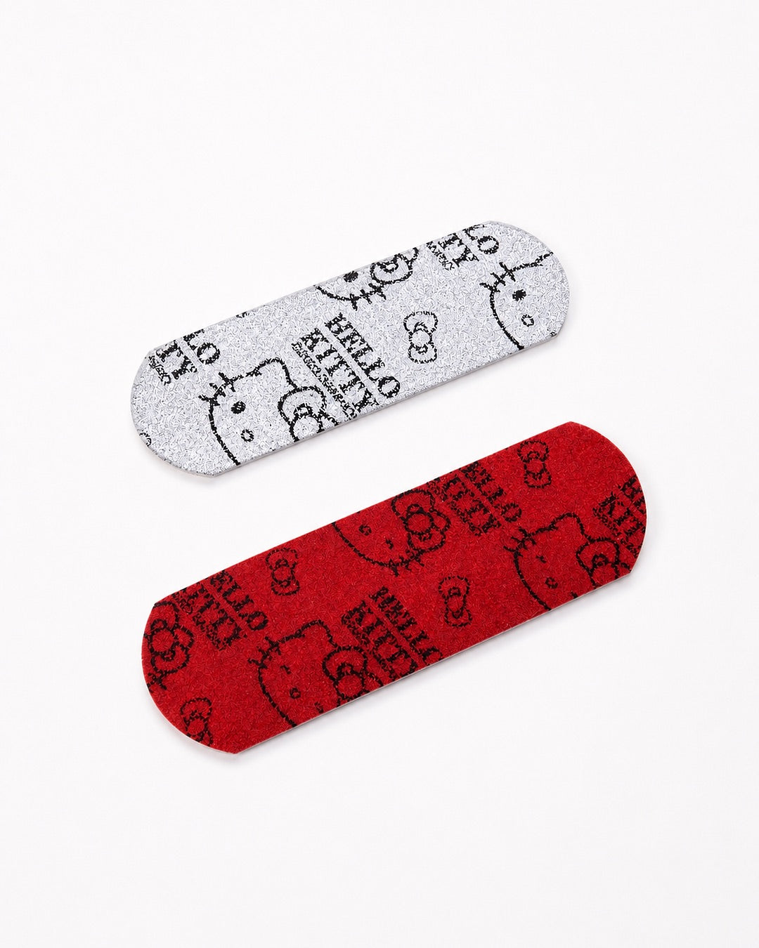 Vue inclinée de deux pansements à paillettes Hello Kitty mettant en valeur l’effet étincelant et texturé de la surface brillante.