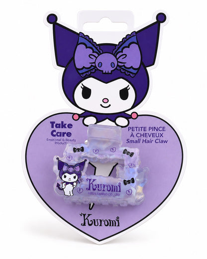 Vue de face de la petite pince à cheveux carrée aux bords ondulés mauve transparent lustré avec le dessin du personnage tenant une rose et le nom de Kuromi inscrit dans son emballage cartonné en forme de cœur mauve.