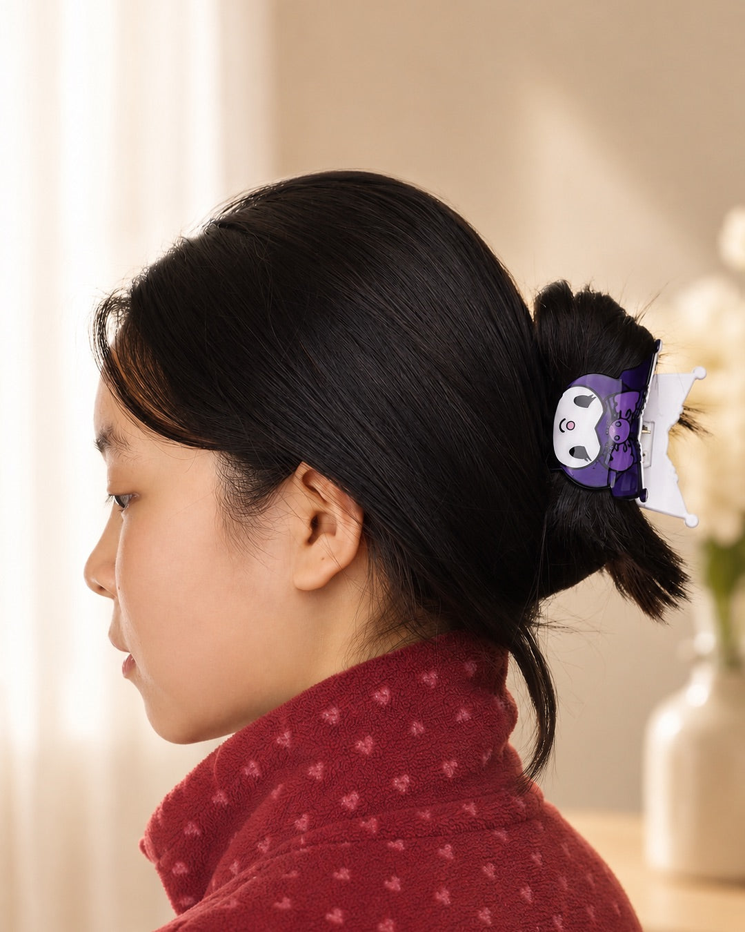 Profil d'une femme portant la petite pince à cheveux crabe à la forme de tête de Kuromi violette et noire de Sanrio pour attacher ses cheveux.