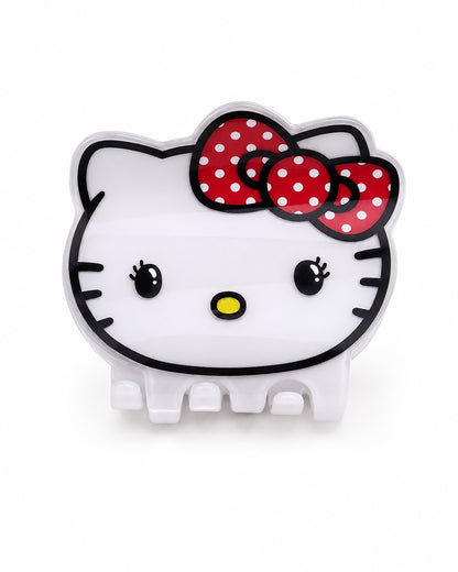 Vue de face d’une pince à cheveux crabe blanche en acrylique moulée en forme de tête complète d’Hello Kitty avec son grand nœud rouge à pois blancs.
