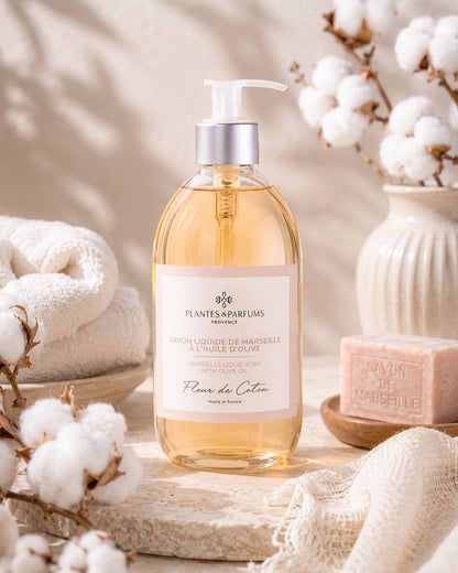 Une bouteille pompe de 500 ml de savon de Marseille liquide, fragrance Fleur de coton, Plantes & Parfums, dans son ambiance olfactive.