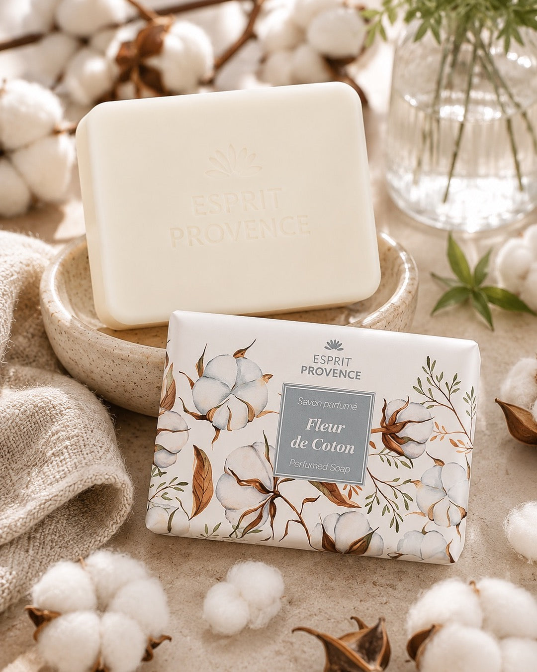 Savon à l’huile d’Amande douce de Provence 140 g, au parfum de Fleurs de coton, signé Esprit Provence et enrichi en beurre de karité BIO. Dans son emballage papier et son ambiance olfactive.