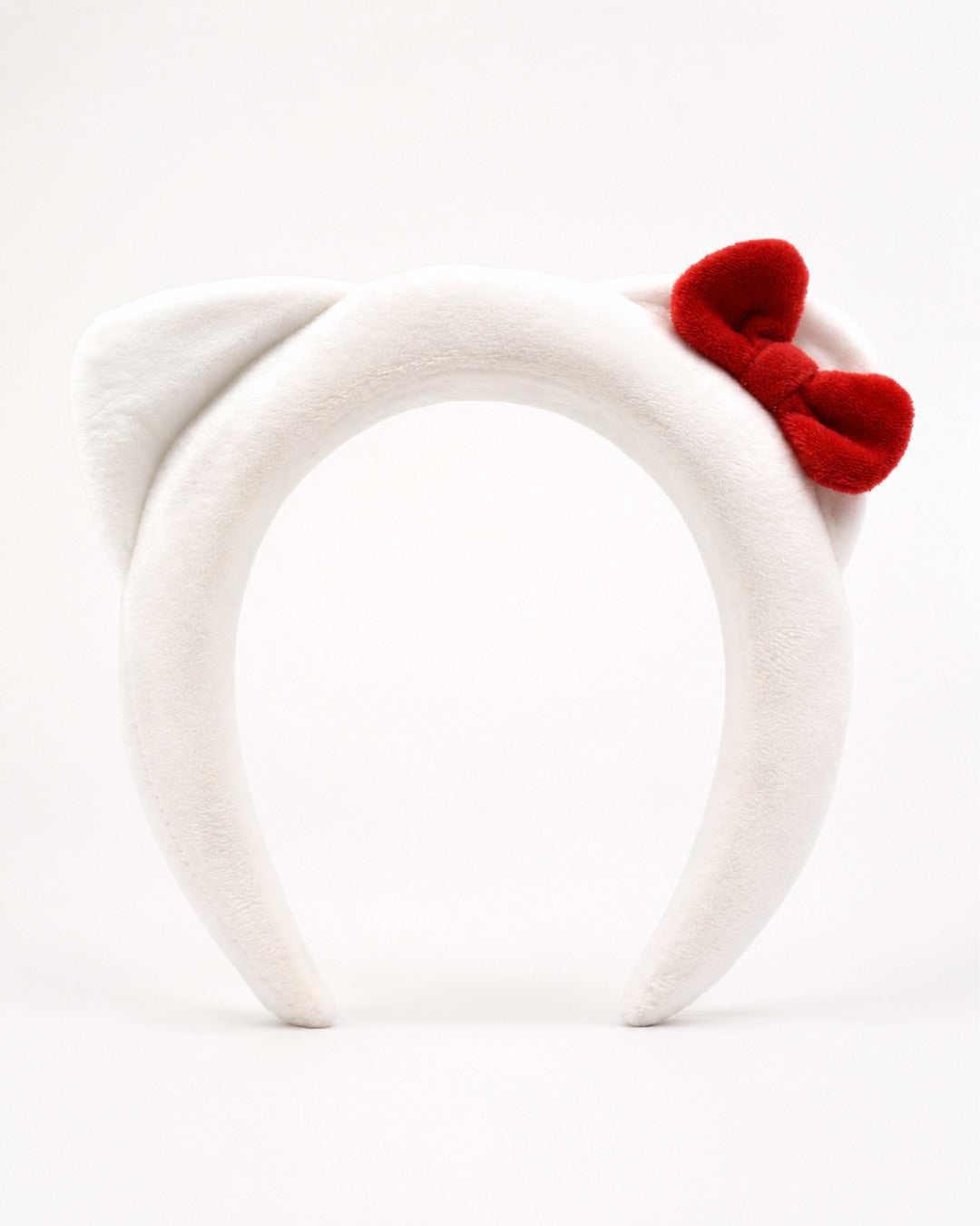 Vue de face du serre-tête en peluche blanche Hello Kitty présenté sur son emballage cartonné d’origine illustrant le visage du personnage.