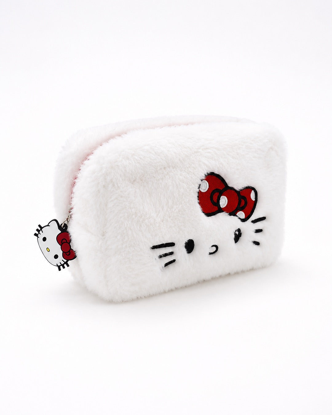 Vue de trois quarts d’une trousse à maquillage rectangulaire en peluche blanche Hello Kitty, brodée avec le visage de la mascotte et son nœud rouge.