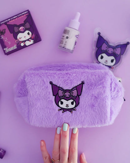 Une main présentant une trousse de maquillage en peluche fausse fourrure violette de  Kuromi Sanrio avec d'autres produits cosmétiques de la même collection.