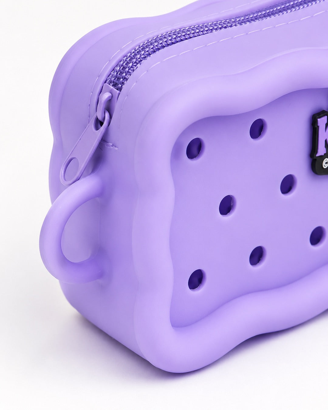 Vue gros plan de biais de la trousse de maquillage en silicone violette Kuromi mettant en valeur l'épaisseur et les bords ondulés.