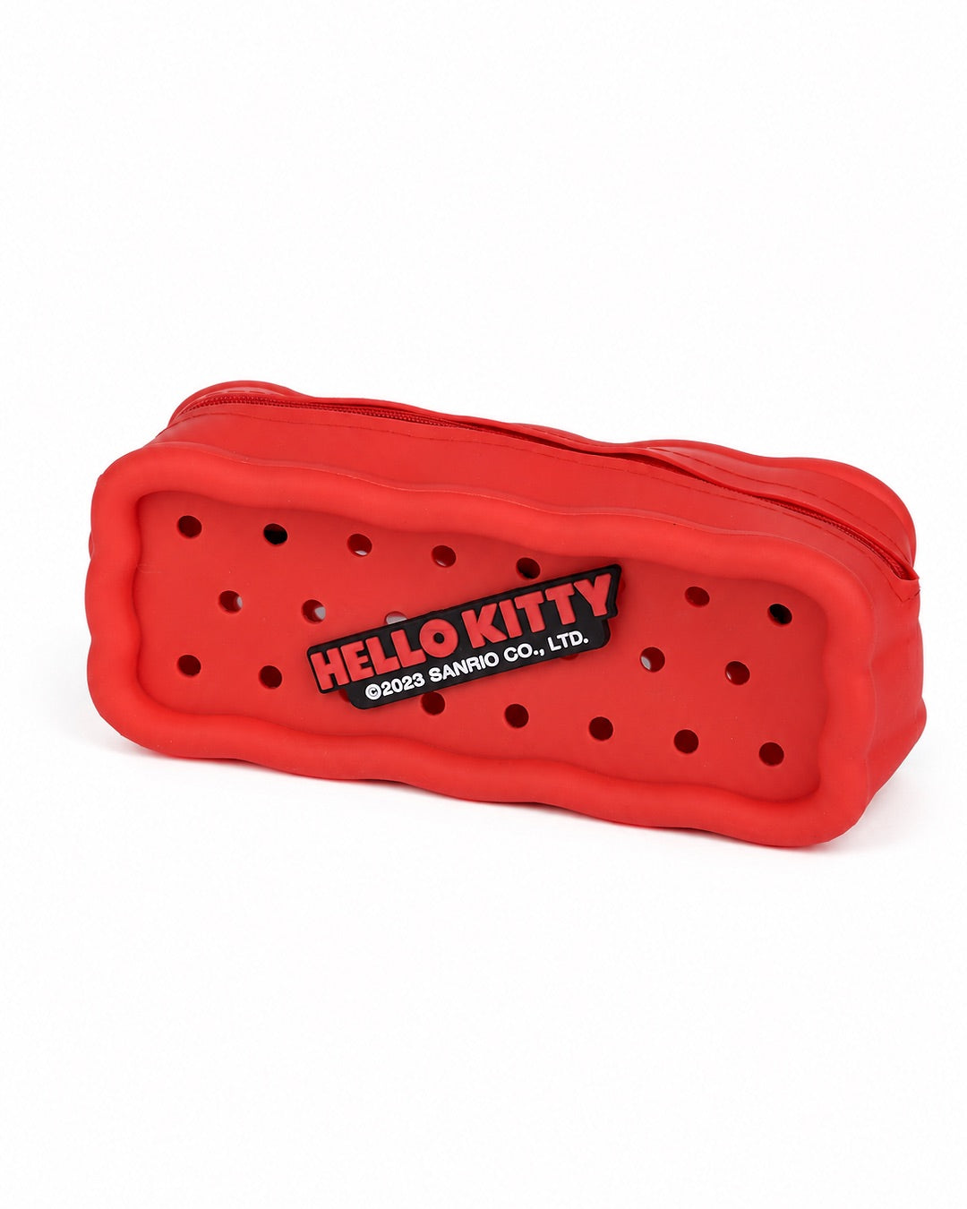 Vue arrière de la trousse rouge en silicone Hello Kitty perforée, affichant une grande plaque noire centrale avec le logo officiel écrit en lettres rouges.