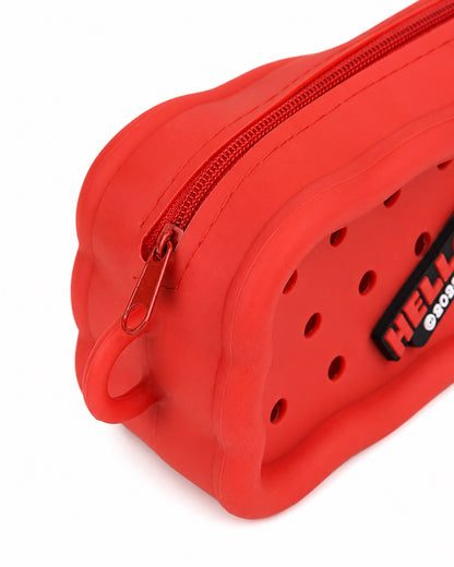 Gros plan détaillé sur l’extrémité de la trousse rouge en silicone, mettant en valeur le fermoir à glissière en métal et la boucle de transport intégrée.
