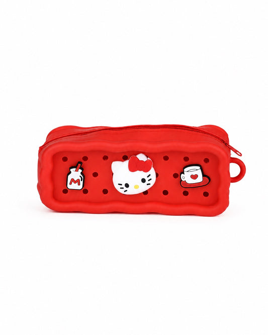 Vue de face d’une trousse rectangulaire rouge en silicone Hello Kitty perforée de petits trous, ornée de charmes amovibles de la mascotte, d’une brique de lait et d’une tasse.